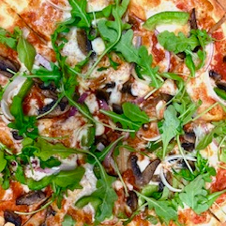 Angolino Pizza's pizza topped with arugula, mushrooms, red onion, and green peppers.